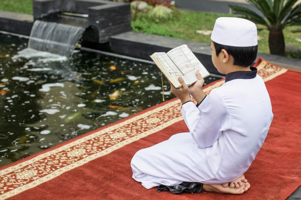 Child reads holy book by a serene pond